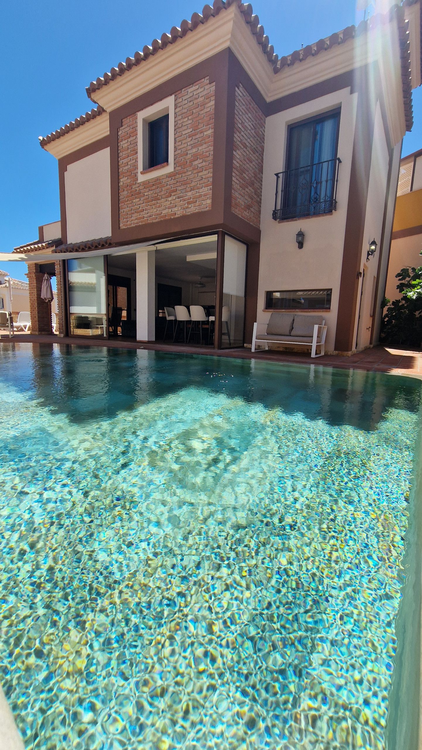 A two-story house with a swimming pool in front.