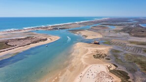 An aerial view of a coastal area with a beach, a boat, and a structure on stilts. - Privilege St George House 5 Bedrooms & Hot Tub in the heart of Fuseta (Fuseta)