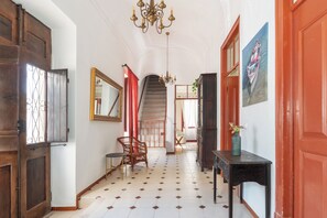 A hallway with a staircase, a chandelier, a mirror, and a painting. - Privilege St George House 5 Bedrooms & Hot Tub in the heart of Fuseta (Fuseta)