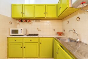 A kitchen with green cabinets, a white microwave, and a stainless steel sink. - Privilege St George House 5 Bedrooms & Hot Tub in the heart of Fuseta (Fuseta)