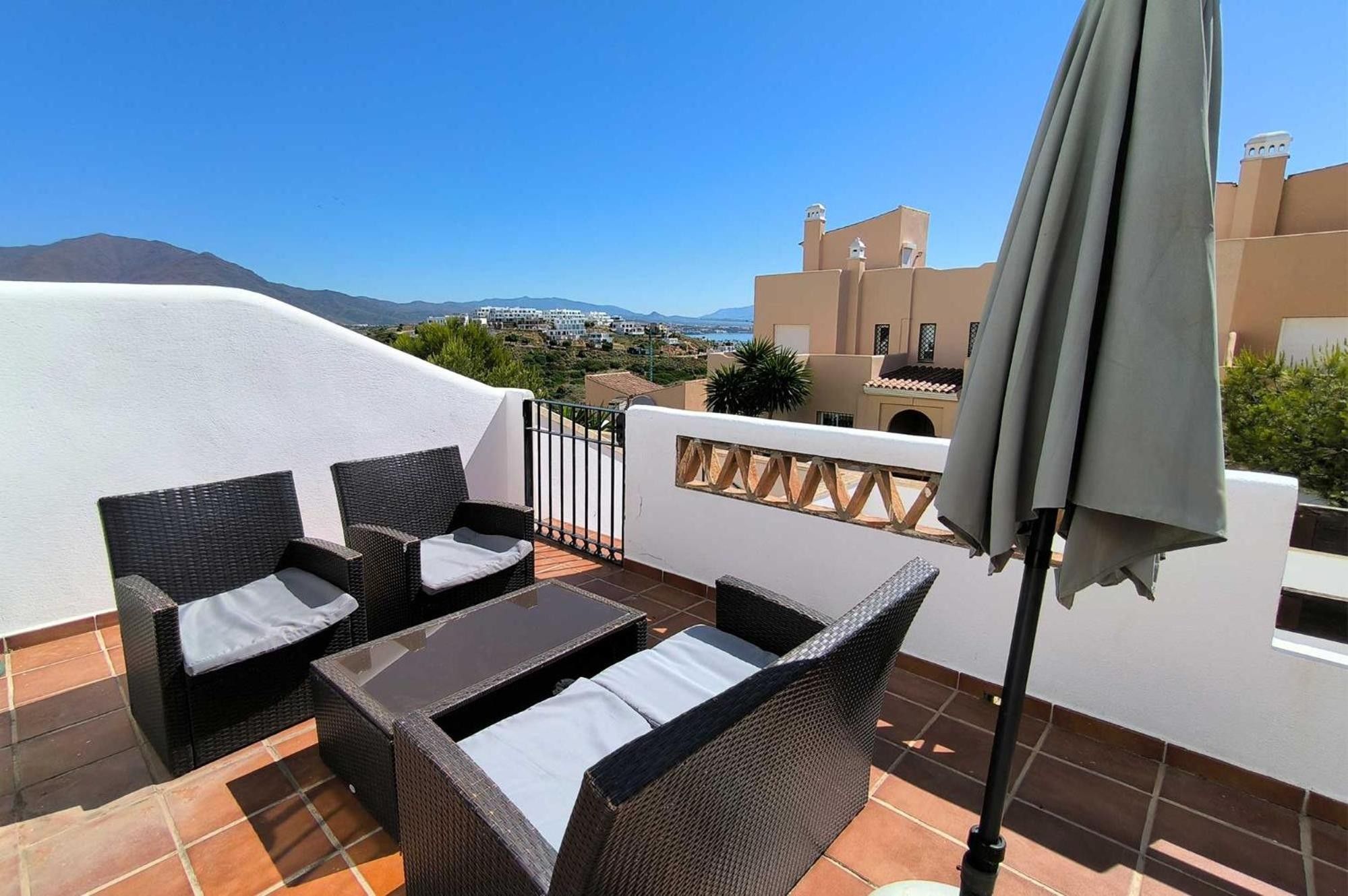 A terrace with wicker furniture, a table, and an umbrella.