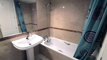 Un baño con lavamanos, bañera y ducha.