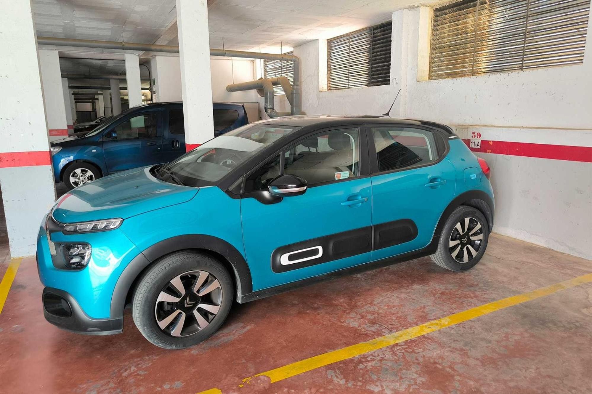 A parking garage with a blue car parked in a designated space.