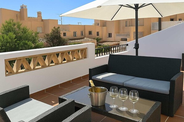 Una terraza en la azotea con un sofá, una mesa y un cubo para champán.