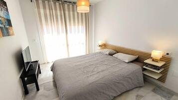 Une chambre moderne avec un grand lit, des lampes de chevet, une télévision et une fenêtre avec des rideaux.