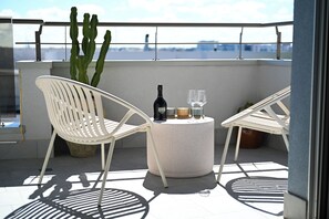 A balcony with two white chairs, a round table with a bottle and glasses, and a cactus plant. - Vimini Horizon (Bari)