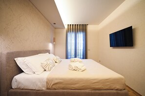 A hotel room with a bed, a flat-screen TV mounted on the wall, and a window with curtains. - Vimini Horizon (Bari)