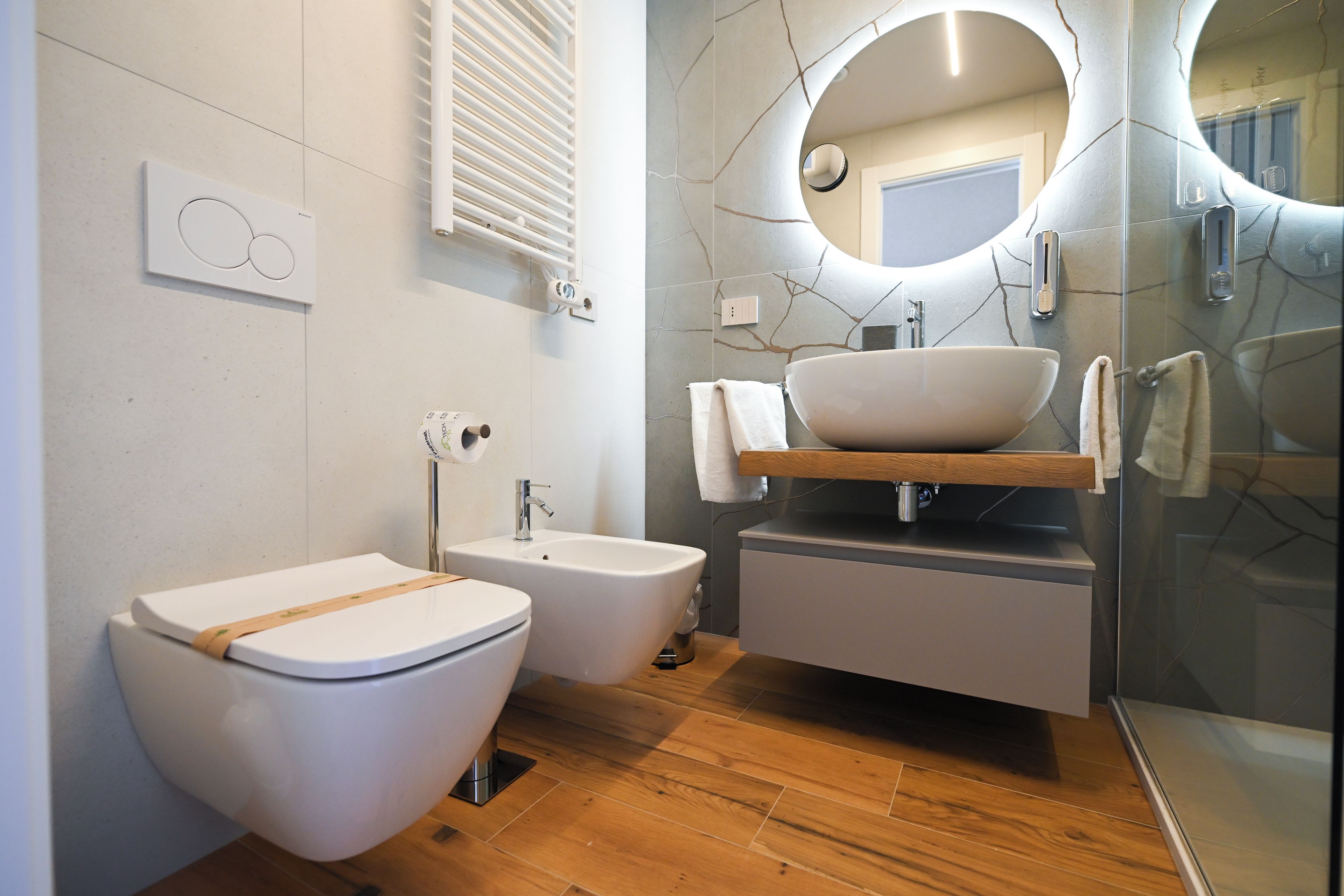 Ein modernes Badezimmer mit Toilette, Bidet und einem Waschbecken in einem Behälter mit einer Holzauslage.