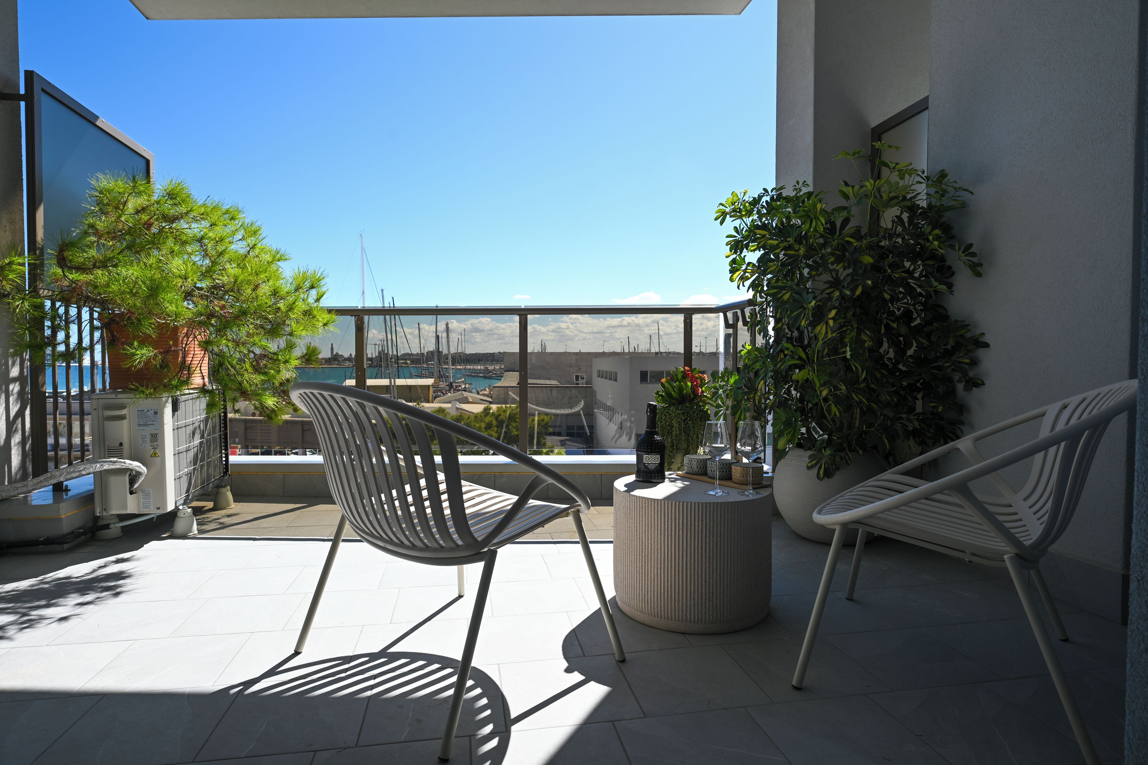 A balcony with two chairs, a round table, and potted plants.