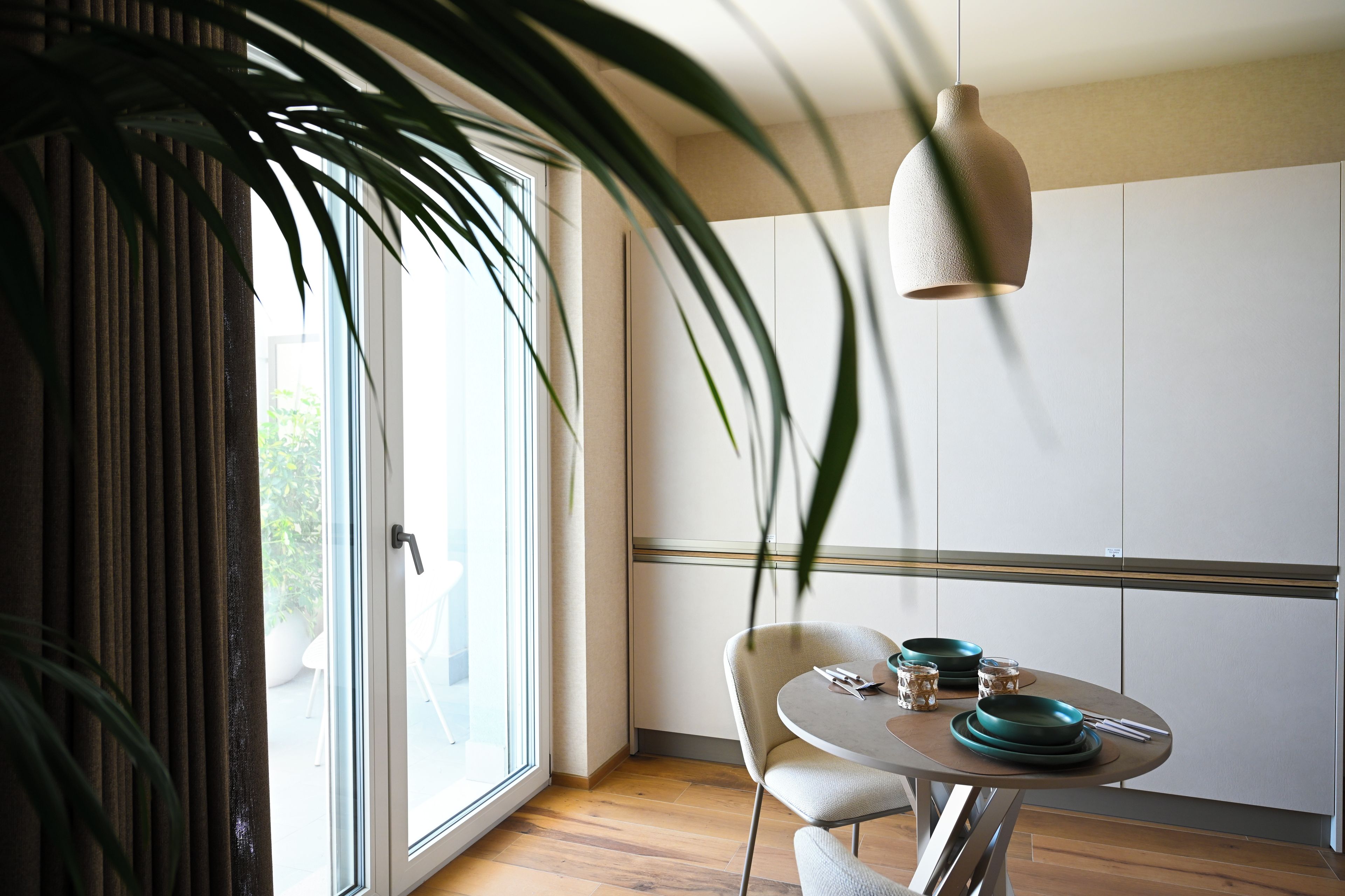 A modern dining area with a round table, chairs, and a hanging light fixture.