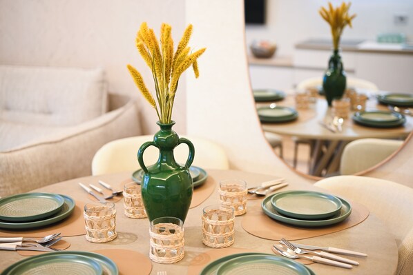 A dining table set with plates, cutlery, and a green vase with yellow flowers. - Vimini Horizon (Bari)