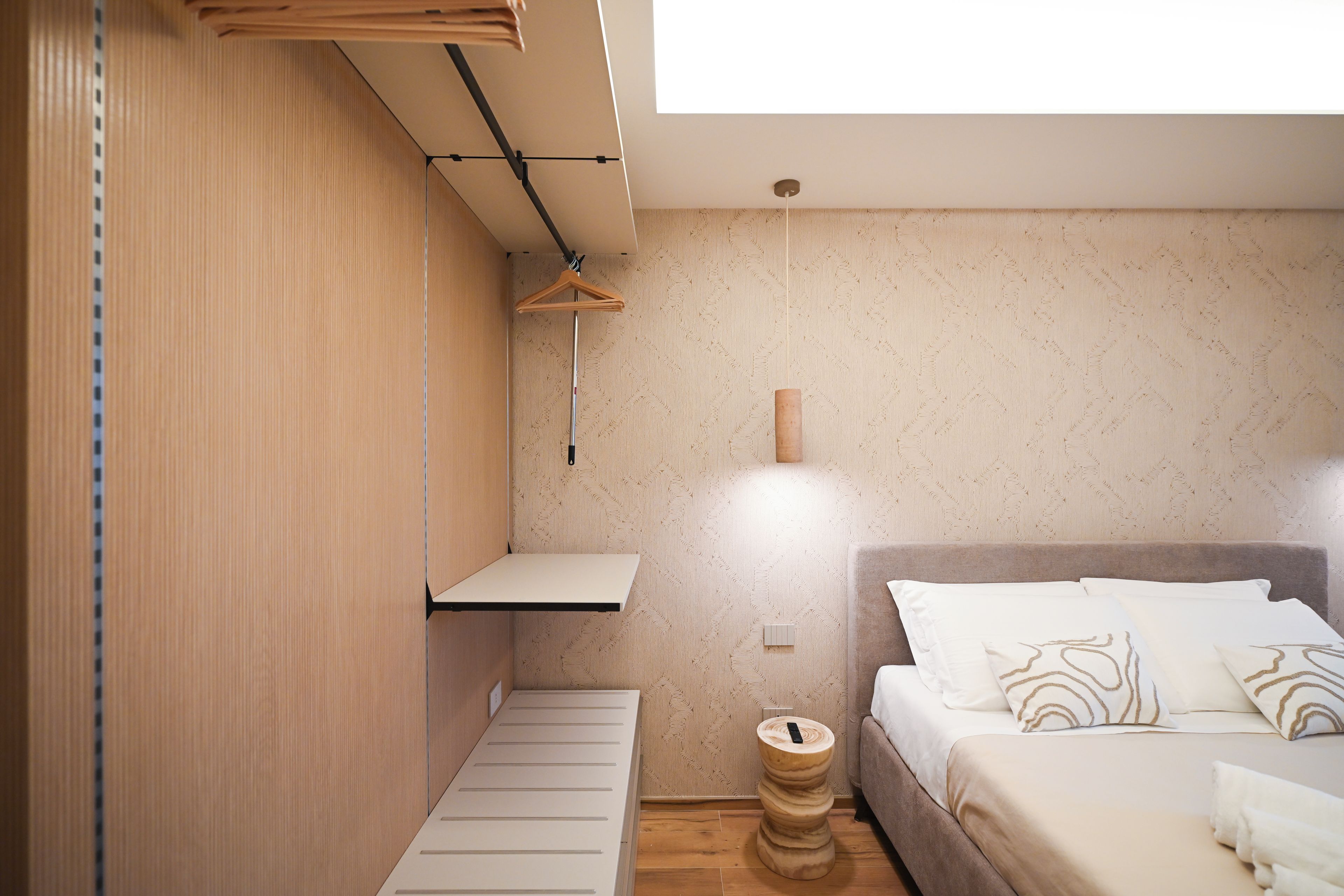 A bedroom with a bed, bedside table, and a hanging light fixture.