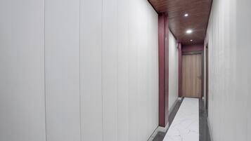 A corridor with white walls, a wooden ceiling, and a marble floor.