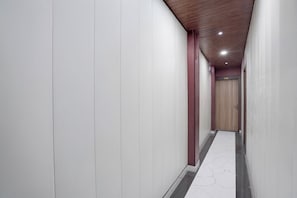 Un couloir aux murs blancs, au plafond en bois et au sol en marbre.