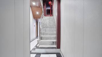 Una escalera de mármol conduce a una habitación con una puerta roja.