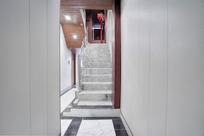 A staircase with marble steps leading to a room with a red door.