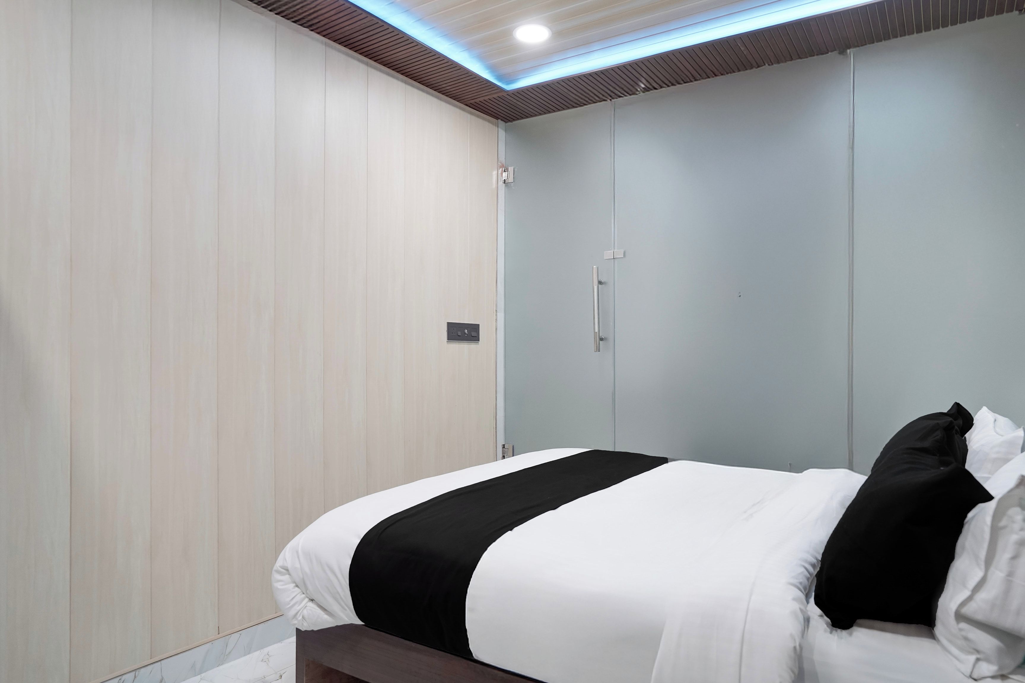 A hotel room with a bed, a wardrobe, and a ceiling with recessed lighting.