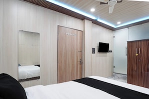 A hotel room with a bed, a wardrobe, a mirror, and a ceiling fan.