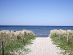 A sandy beach path leading to the ocean, flanked by grass and wooden posts. - Achtern Diek 12c - Apartment 3 (Zingst)