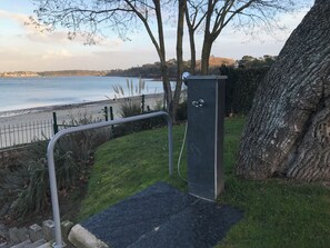 A pathway leading to a beach with a metal railing, a stone structure, and a tree. - Exceptional duplex overlooking Saint-Malo in a private estate—with direct access to the beach (Dinard)
