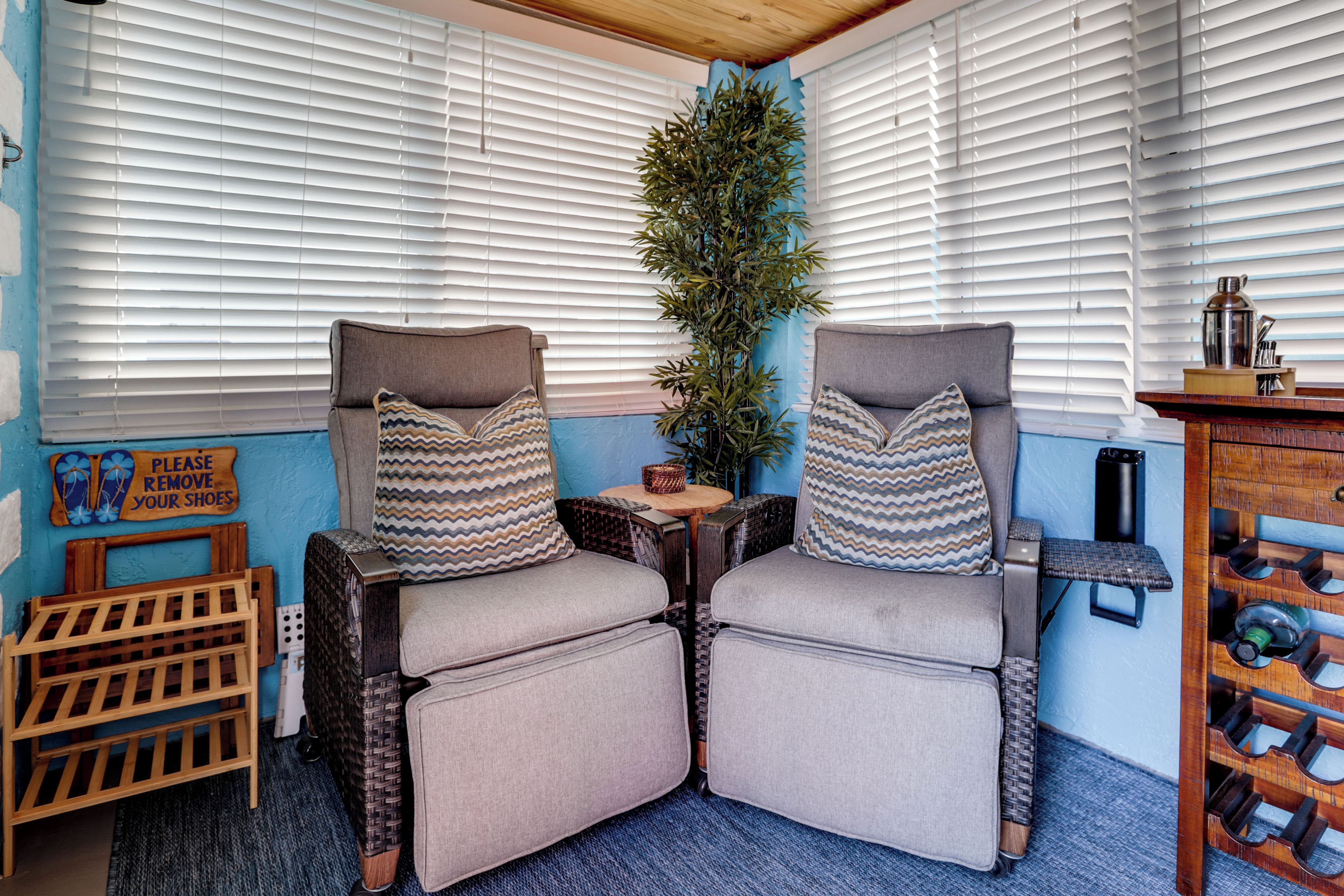 A room with two armchairs, a small table, a plant, and a shoe rack.