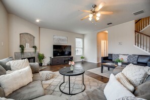 A modern living room with a fireplace, comfortable seating, a flat-screen TV, and a ceiling fan. - 7 Mi to Seaworld! Group-friendly Getaway w/ Pool (San Antonio)