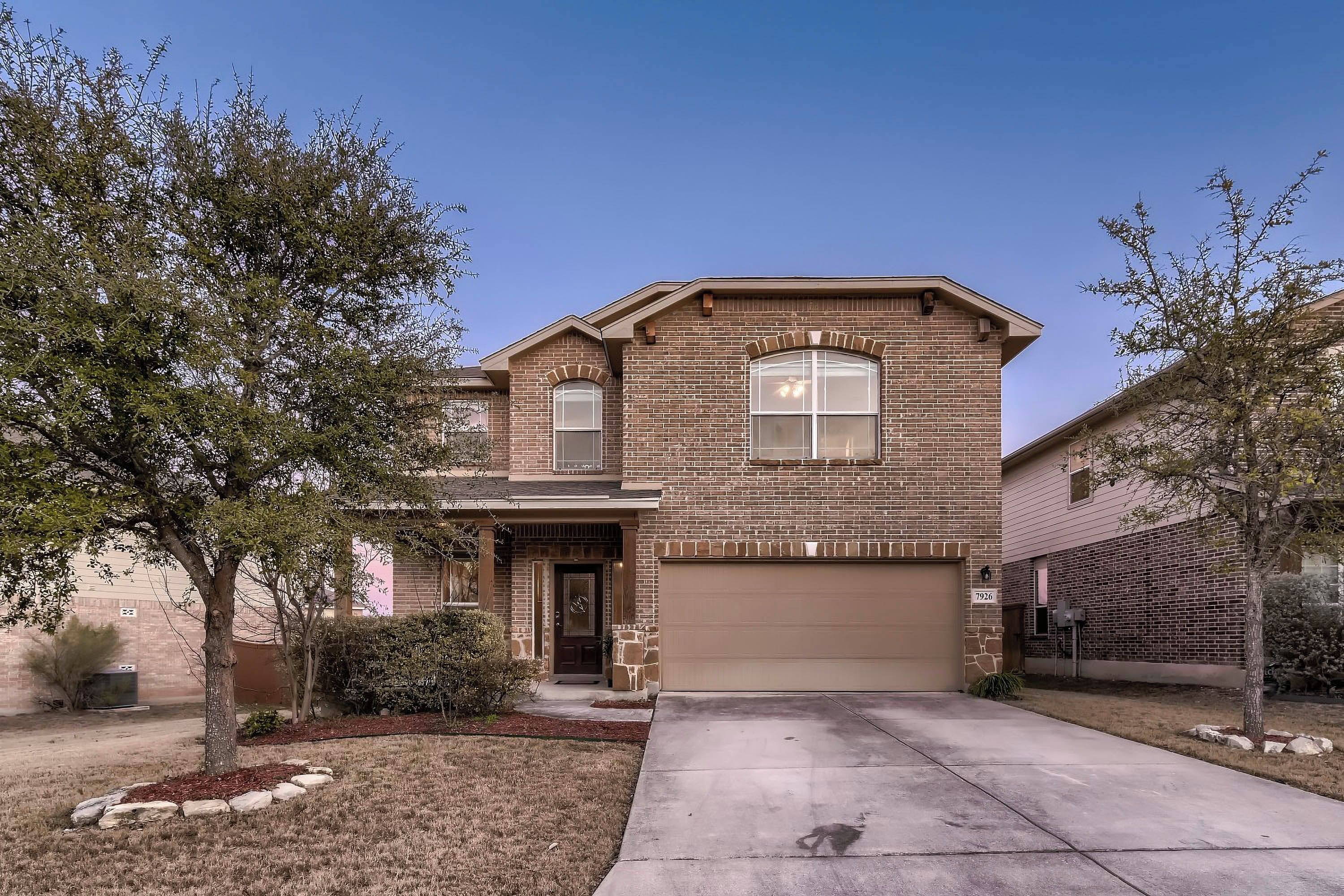 A two-story house with a brick facade, a garage, and a front yard with landscaping.