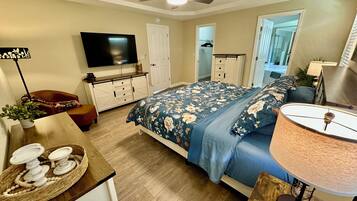 Une chambre à coucher comprenant un lit, une télévision, un ventilateur de plafond, une commode et une lampe.