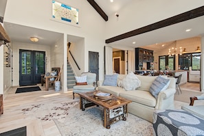 A spacious living area with a high ceiling, a staircase, and a kitchen visible through an open door. - A Long Way From Durrow (Sautee Nacoochee)