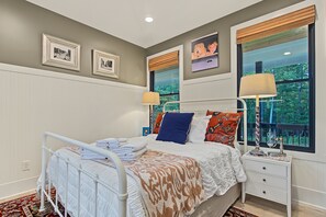 A bedroom with a bed, bedside tables, a window with a view, and wall-mounted artwork. - A Long Way From Durrow (Sautee Nacoochee)