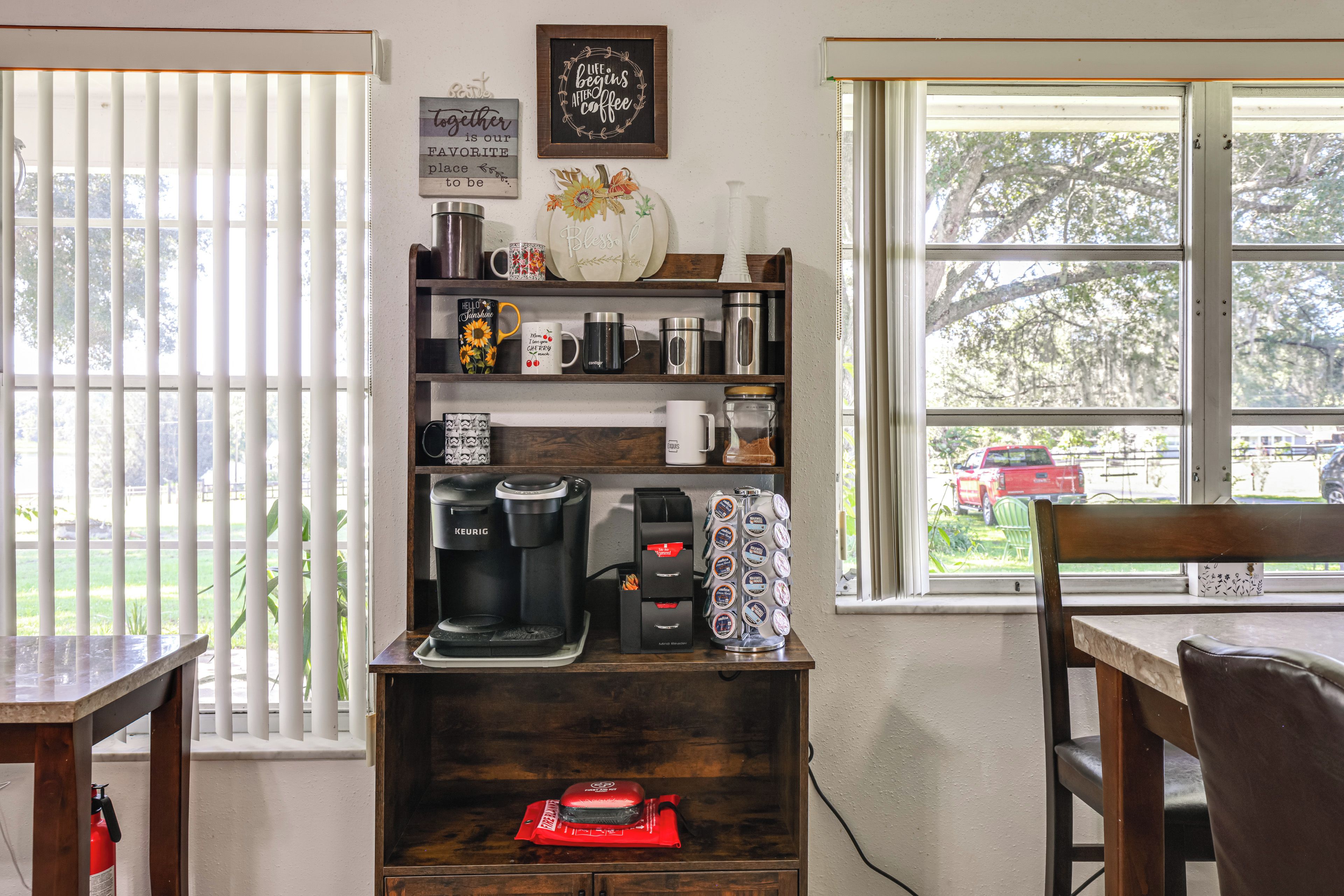 A kitchen with a coffee maker, mugs, and a coffee grinder on the counter.