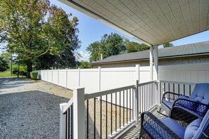A covered outdoor seating area with a white fence, gravel ground, and a building in the background. - New To Market Riverfront Pigeon Forge Retreat (Pigeon Forge)