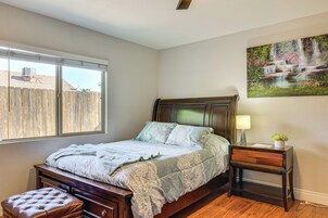 Un dormitorio con una cama, un banco de madera, una mesita de noche con una lámpara y un cuadro de una cascada.