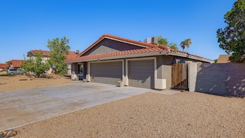 A residential house with a garage, driveway, and gravel driveway.