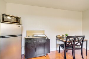Una cocina compacta con microondas integrado, un refrigerador y un mueble de madera con encimera.