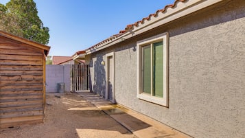 Un edificio con techo de metal corrugado, estructura de madera a la izquierda y un sendero pavimentado que lleva a una puerta.