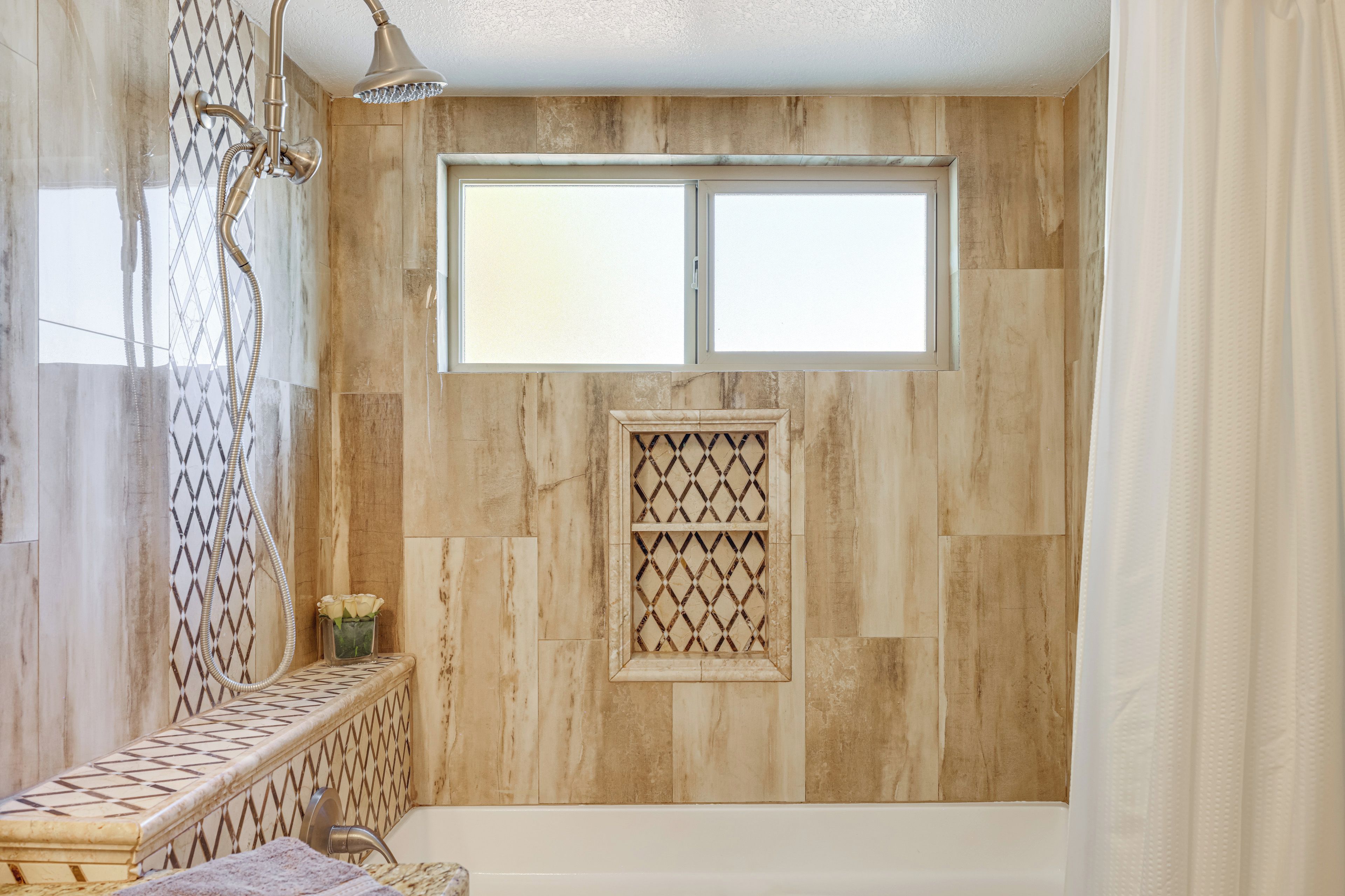 A bathroom with a bathtub, a window, and a shower with a glass door.