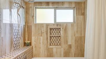 A bathroom with a bathtub, a window, and a shower with a glass door.