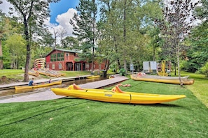 A riverside property with a red building, a dock, and several kayaks. - Waterfront Studio Cabin on Rock Springs Run! (Apopka)