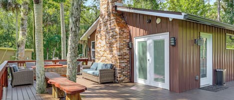 A wooden deck with outdoor furniture, a stone fireplace, and a metal door.