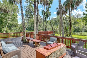 A wooden deck with outdoor furniture, surrounded by trees and a clear sky. - Waterfront Studio Cabin on Rock Springs Run! (Apopka)
