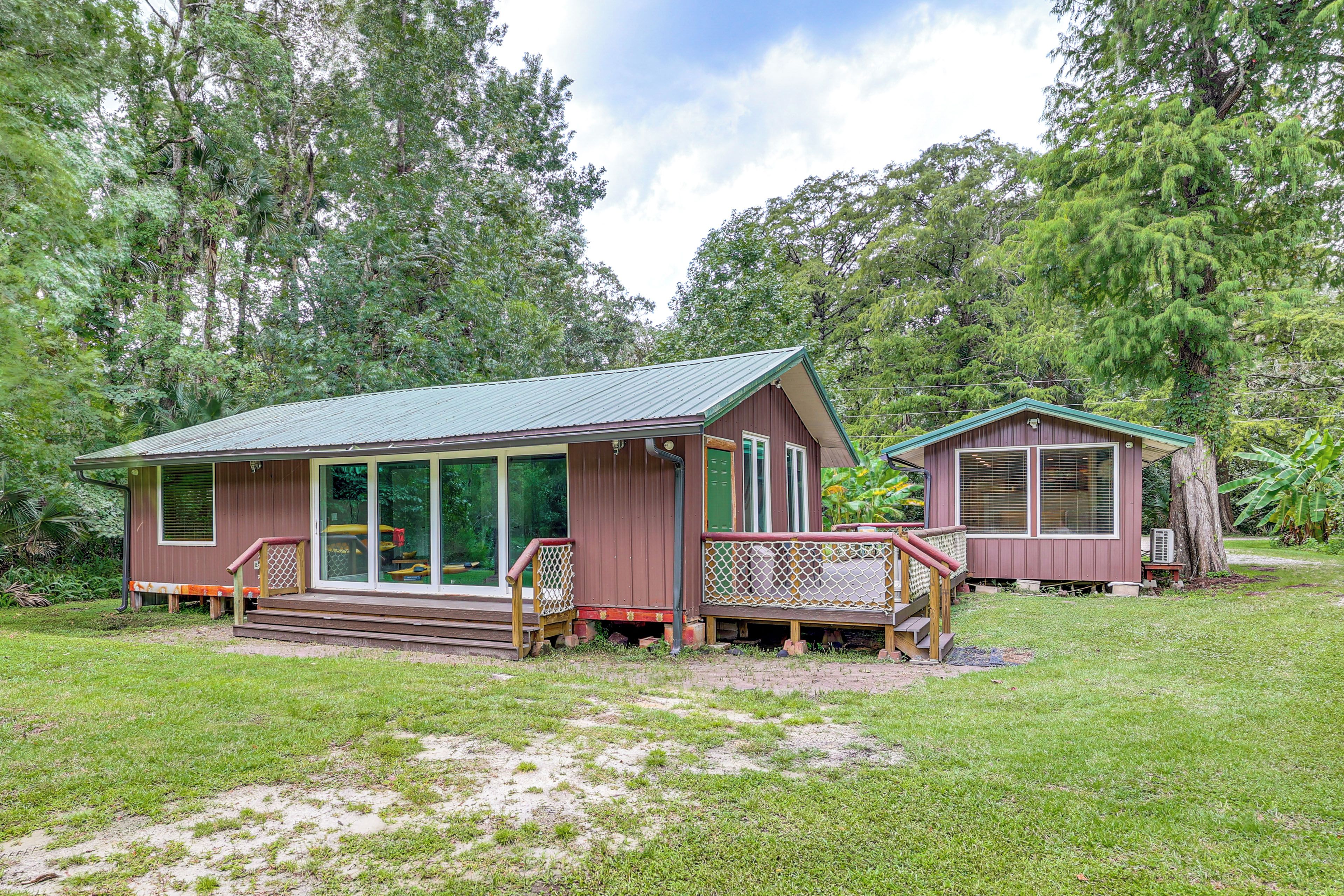 Two cabins with a grassy yard and trees in the background.