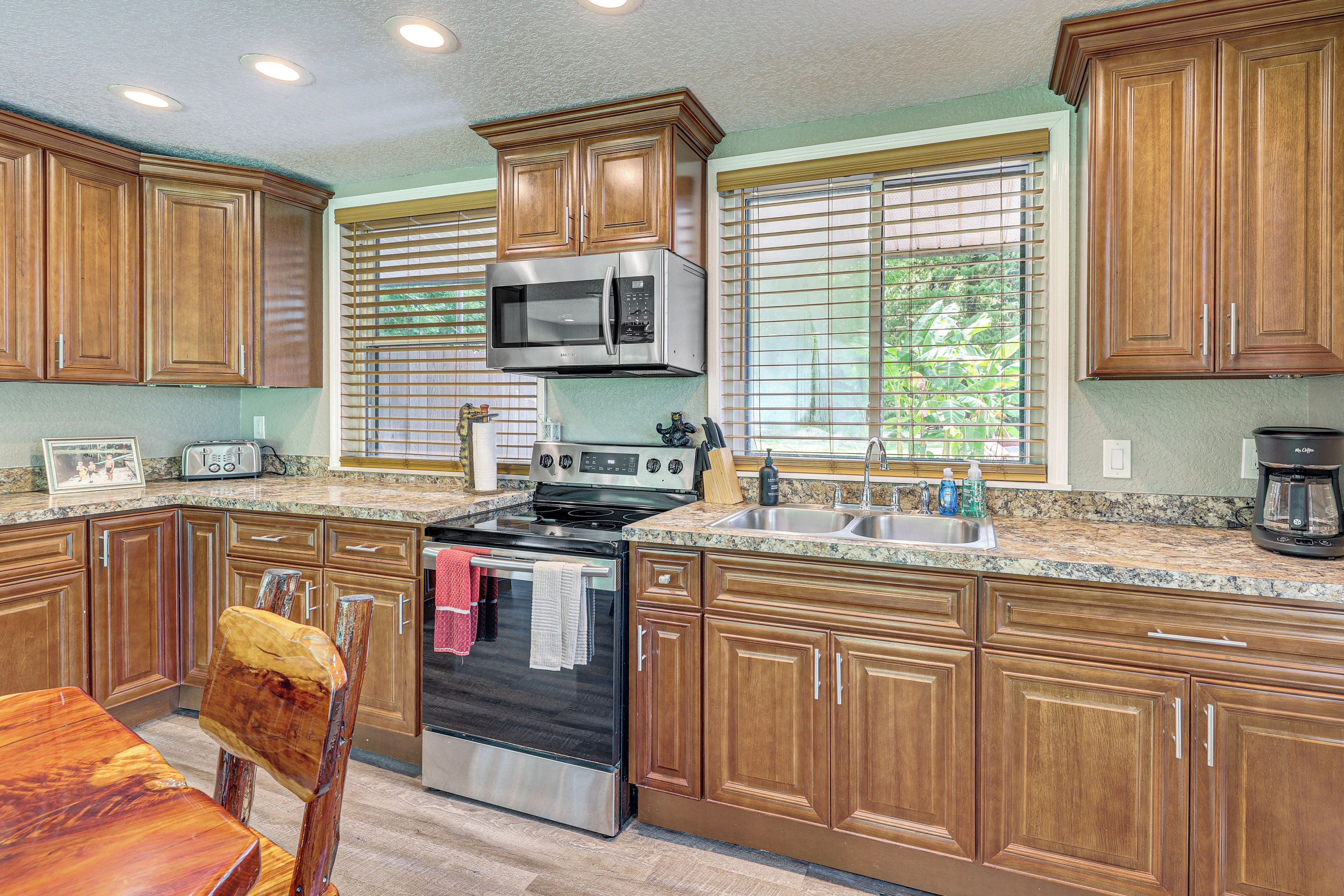 A kitchen with wooden cabinets, a stainless steel microwave, a stove, and a sink.
