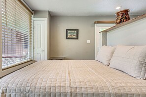 A bedroom with a bed, a window with blinds, a door, and a framed picture on the wall. - Waterfront Studio on Rock Springs River! (Apopka)