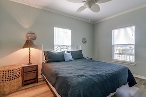 A bedroom with a bed, a nightstand, a lamp, a wall clock, and two windows with blinds. - 3 Block to Ocean! Walkable Crystal Beach Retreat (Port Bolivar)