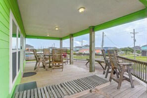 A covered outdoor area with wooden chairs and tables, a wooden deck, and a view of the surrounding neighborhood. - 3 Block to Ocean! Walkable Crystal Beach Retreat (Port Bolivar)