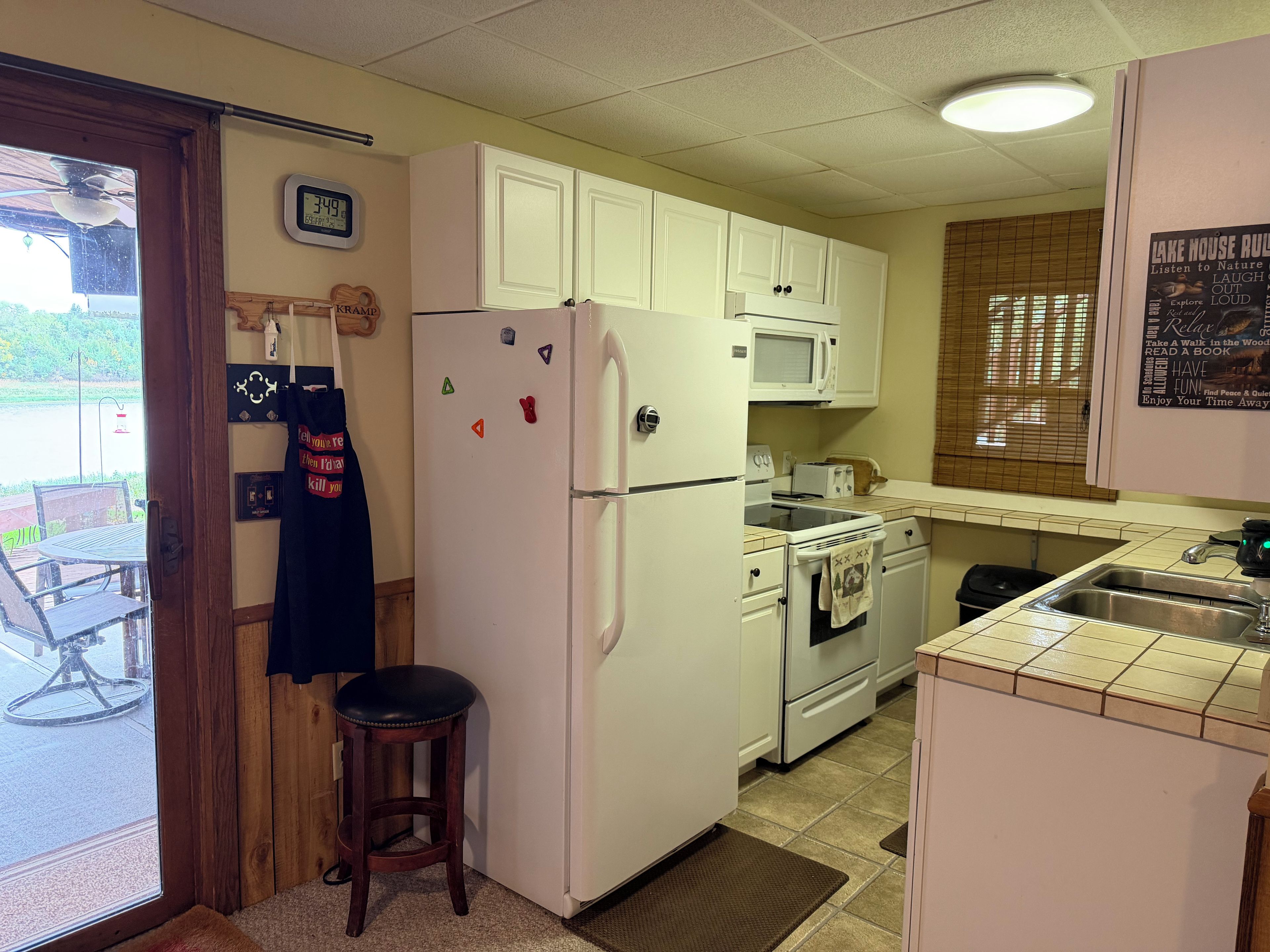 Cocina compacta con armarios blancos, refrigerador, microondas y estufa.