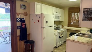Cocina compacta con armarios blancos, refrigerador, microondas y estufa.