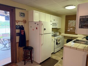 A compact kitchen with white cabinets, a refrigerator, a microwave, and a stove.