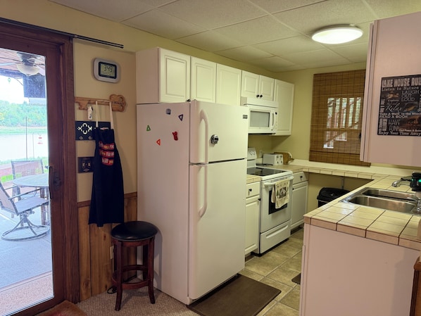 A compact kitchen with white cabinets, a refrigerator, a microwave, and a stove.